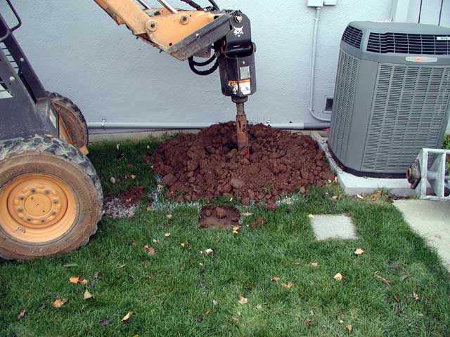 Bobcat with auger drilling into ground